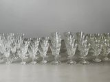 twelve crystal wine glasses lined up in a row on a table