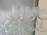 many wine glasses sitting on a glass shelf in a room