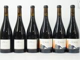 six bouteilles de vin sont alignées sur une surface blanche