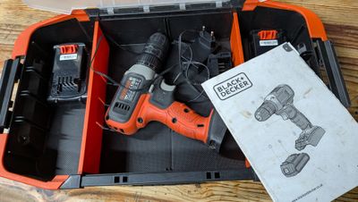 une perceuse sans fil orange et noire et deux batteries dans un étui