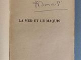 un livre ouvert, sur lequel figure un titre écrit à la main, posé sur une surface bleue
