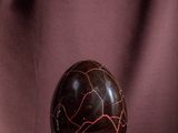 an egg with a cracky surface sits on a purple cloth