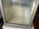 un petit réfrigérateur surmonté d'une porte vitrée