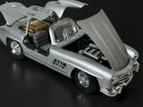a silver toy car with its hood open on a black surface