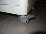 a white suitcase that is sitting on wheels on the floor