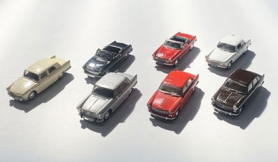 plusieurs petites voitures sont alignées sur une surface blanche