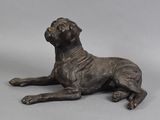 statue en bronze représentant un chien couché sur une surface grise