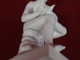 a white statue of a man sitting on top of a box