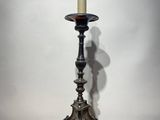 a black candle holder sitting on top of a wooden floor next to a white wall