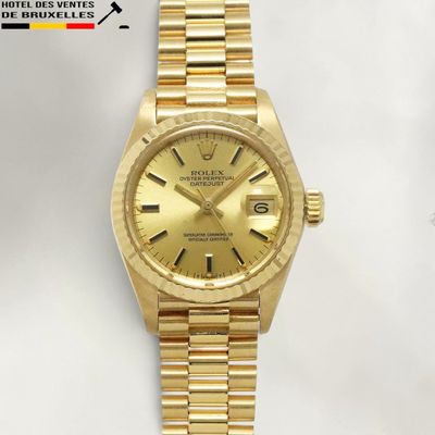 an image of a gold rolex watch sitting on a white surface