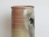 a brown and black vase sitting on a white surface
