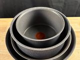 three bowls and a plate on a wooden table with a black background