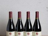 Quatre bouteilles de vin rouge sont alignées sur une table en bois