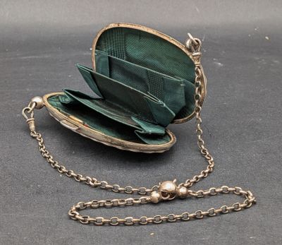 a green purse with a chain around it on a table
