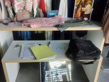 a white shelf with clothes on it in a room