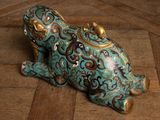 a figurine of a frog sitting on a wooden floor