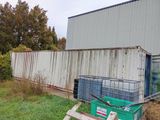 a green container sitting in the grass next to a building