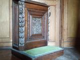 une armoire en bois posée à même le sol, avec un coussin vert dessus