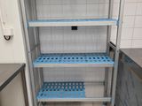 a blue shelf in the middle of a white tiled room
