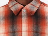 a close up of a man wearing a red and black checkered shirt
