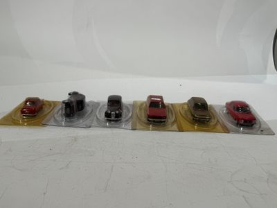 five toy cars are lined up in a row on a white surface