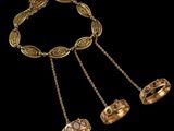 a gold necklace with three rings and a chain on a black background