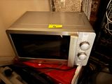 un micro-ondes argenté posé sur une table rouge