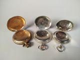 several silver pocket watches and a keychain on a white surface