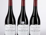 trois bouteilles de vin rouge posées sur une table blanche