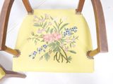 a yellow chair with a floral design on the back of it