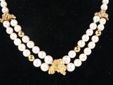 a necklace with pearls and gold beads on a black mannequin