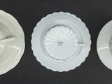 three white plates and a bowl on a black surface