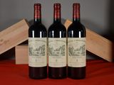 trois bouteilles de vin rouge posées à côté d'une caisse en bois sur une table
