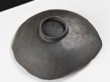 a black bowl sitting on a white table with a black background