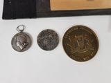 three coins and a medal on a table next to a book
