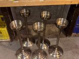 four metal candles sitting on top of a wooden shelf