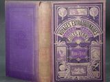 an old book with a purple cover sitting on top of a table