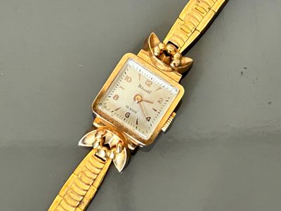 an image of a gold wrist watch with a chain around it