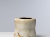 un petit vase blanc posé sur une table blanche