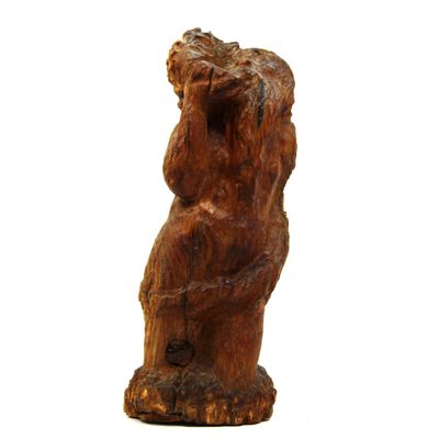 une statue en bois représentant un ours assis sur une souche d'arbre