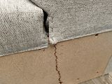 a crack in the back of a couch that has been wrapped in plastic