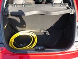 the trunk of a red car with a hose in the trunk