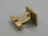 an image of a pair of gold cufflinks on a gray surface