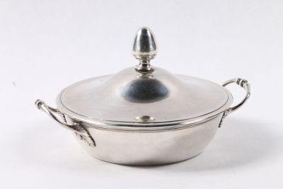 une casserole en argent avec un couvercle, posée sur une surface blanche