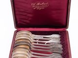 six silver spoons in a red case on a white surface