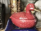 a red duck sitting on top of a blue plate
