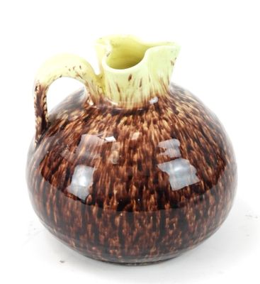 un vase marron et blanc, muni d'une anse jaune sur un fond blanc