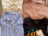 three shirts and a shirt hang on a clothes rack on a wooden floor