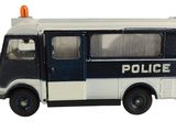 un camion de police miniature posé sur une surface blanche