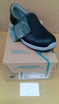 des chaussures sans lacets noires et blanches dans une boîte posée sur une table